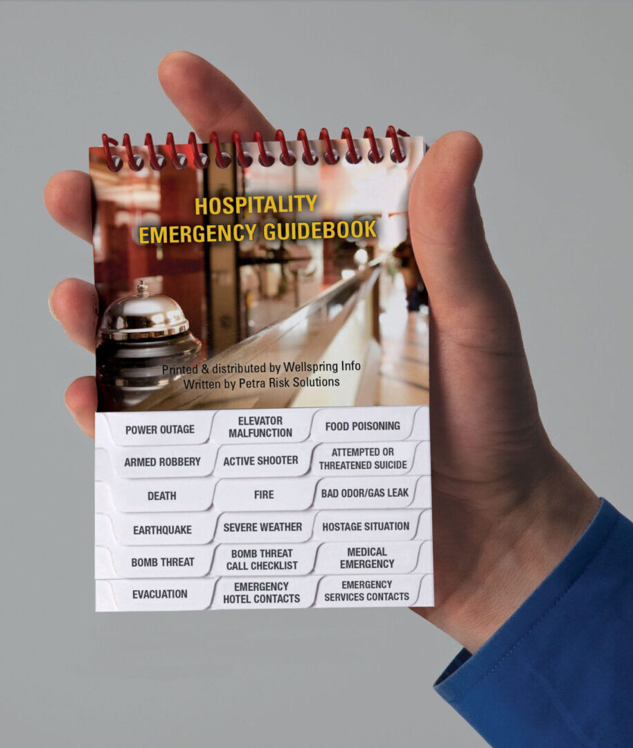 A hand holding a notepad with the words " hospitality emergency instructions ".